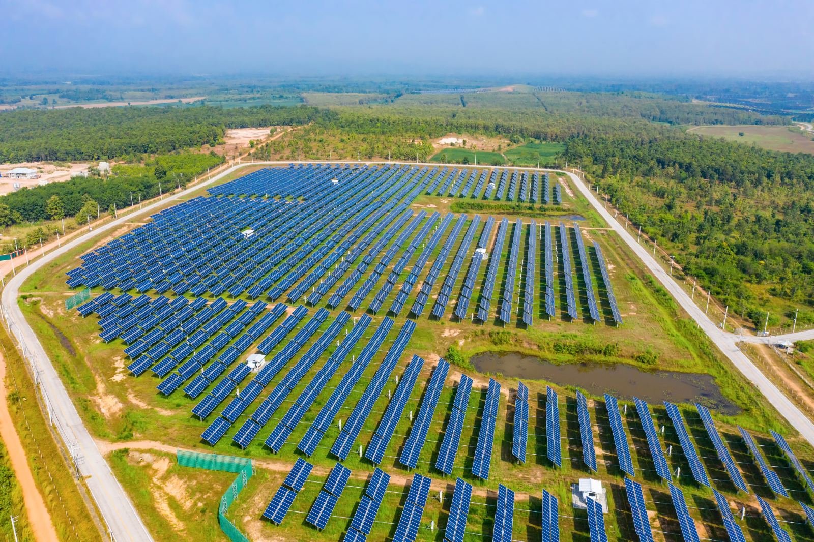 Aerial view of a large ground-mounted solar farm with perimeter access road